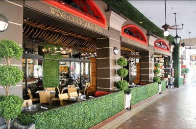 Exterior of City Cellar, red awnings and outdoor seating with brick roadway in front. 