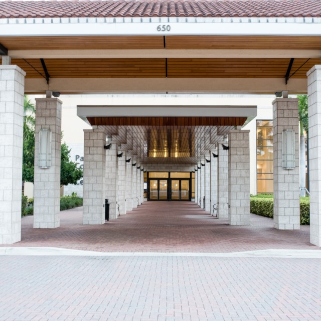 Photo of ground level vie looking down the center of the covered front walkway to the main front door entrance